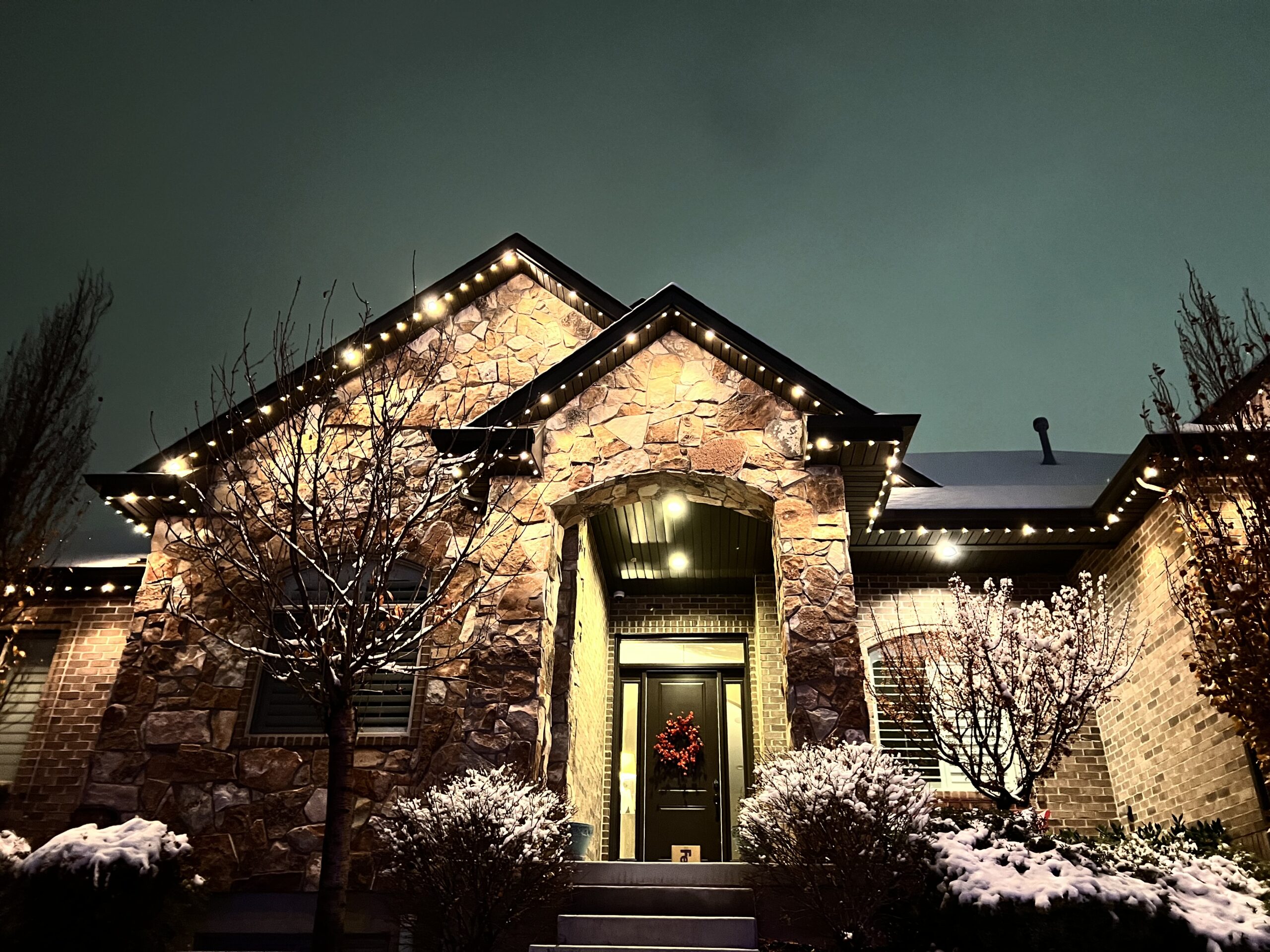 A charming residence featuring bright lights on the front and side, enhancing its inviting appearance at night.