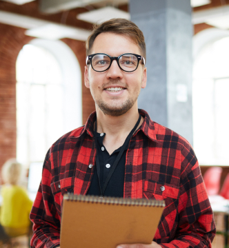 A man wearing glasses is holding a clipboard, appearing focused and engaged in his task.