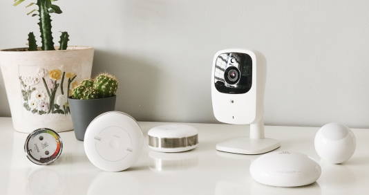 A white table displaying an array of smart home devices, including a sleek camera, showcasing modern technology.