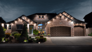 A charming residence with bright lights adorning the driveway, enhancing the welcoming ambiance of the property at night.